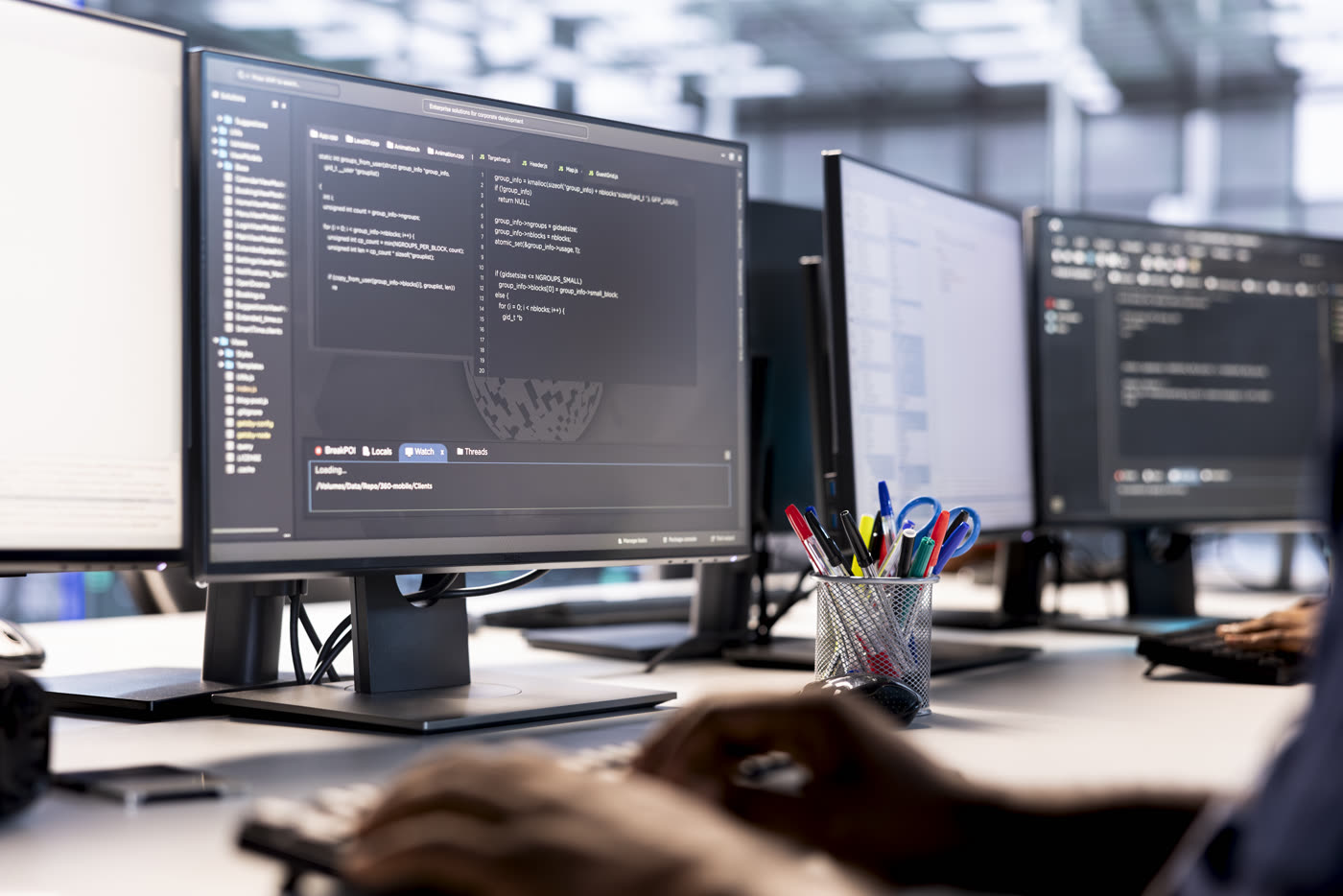 Profesional de sistemas optimizando código en varios monitores